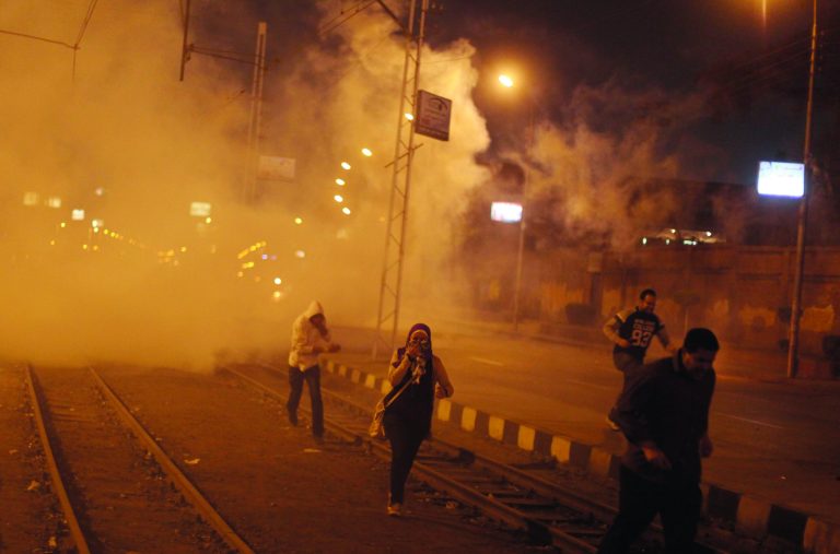 Egyptian protesters run for cover from tear gas fired by riot police, not seen, during clashes next to the presidential palace in Cairo, Egypt, Monday, Feb. 11, 2013. Security forces sprayed protesters with water hoses and tear gas outside the presidential palace Monday as Egyptians marked the second anniversary of autocrat Hosni Mubarak's ouster with angry demonstrations against his elected successor.(AP Photo/Khalil Hamra)