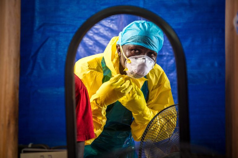 FILE - In this Thursday, Oct. 16, 2014 file photo, a healthcare worker dons protective gear before entering an Ebola treatment center in the west of Freetown, Sierra Leone. (AP Photo/Michael Duff, File)