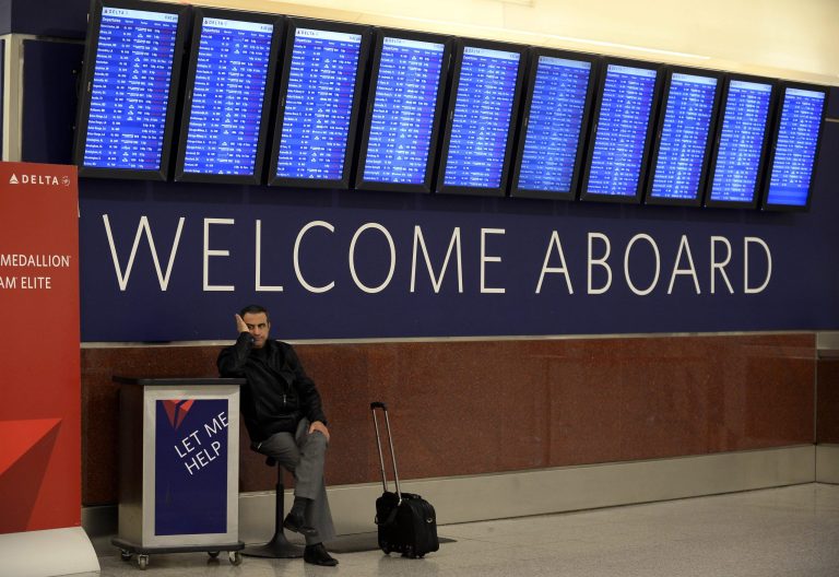 Airline passenger Hossam Shalaby, from Egypt, waits for his rescheduled flight to Orlando under the departure board showing hundreds of cancellations at Hartsfield-Jackson International Airport on Tuesday, Feb. 11, 2014 in Atlanta. The city dodged the first punch of a dangerous winter storm Tuesday, but forecasters warned of a potentially 