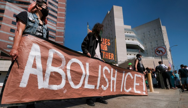 Protesters display a sign that reads "Abolish ICE" during a rally in front of the Immigration and Customs Enforcement facility in downtown Los Angeles on Monday, July 2, 2018. Protesters who were blocking the entrance to an Immigration and Customs Enforcement facility in downtown Los Angeles have been led away in handcuffs. A group of 17 protesters sat down in the street, blocking the entrance to the facility Monday morning. The protesters, including faith and community leaders, locked arms and chanted, "Shut down ICE!"