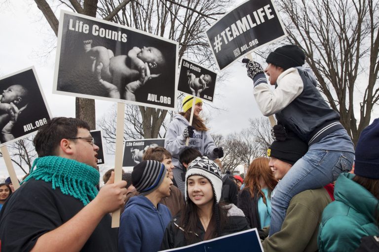 Rosie Mami, center, and her sister Ayleana Mami, 19, of Cullman, Ala., right, sit on their friends' shoulders as they lead a chant about loving babies, with other members of St. Bernard Prep, as anti-abortion demonstrators rally at the annual March for Life, Thursday, Jan. 22, 2015, on the National Mall in Washington. (AP Photo/Jacquelyn Martin)