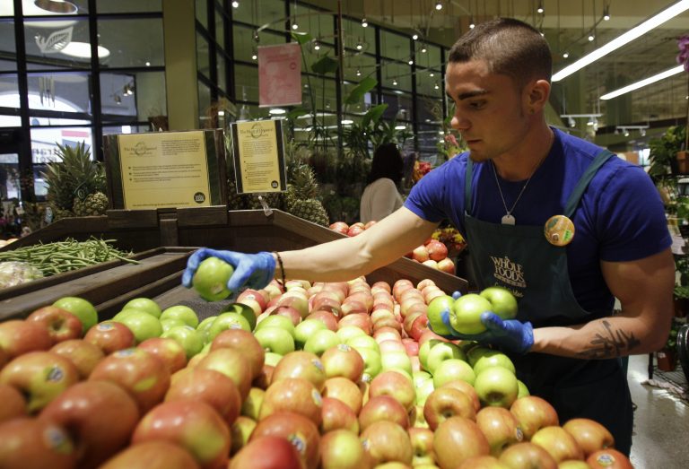 FILE - In this Nov. 3, 2010 file photo, Victor Hernandez stocks apples in the produce section at Whole Foods, in Coral Gables, Fla. Whole Foods on Wednesday, Oct. 15, 2014 plans to start rolling out a system that ranks fruits and vegetables as 
