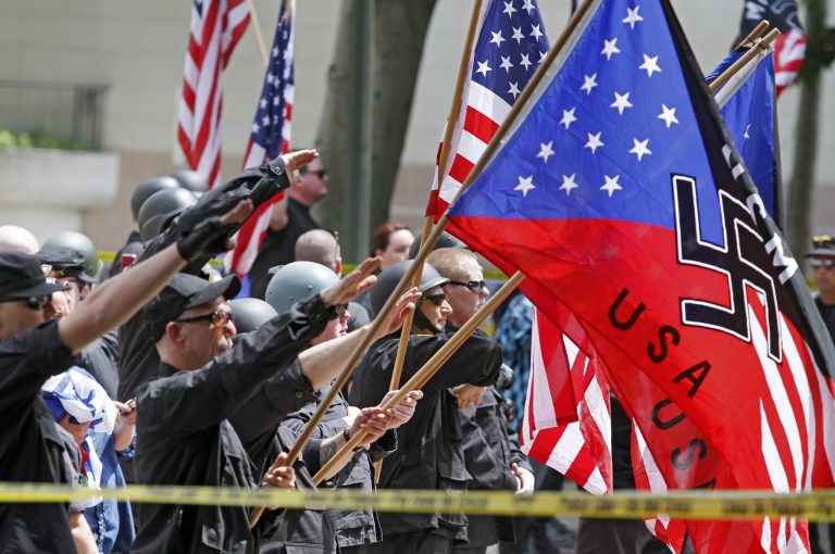A white supremacist group salutes American flags and banners with swastikas at Los Angeles City Hall on Saturday, April 17,2010. Hundreds of counter-protestors carrying anti-Nazi signs have gathered in downtown Los Angeles where a white supremacist group is rallying.
