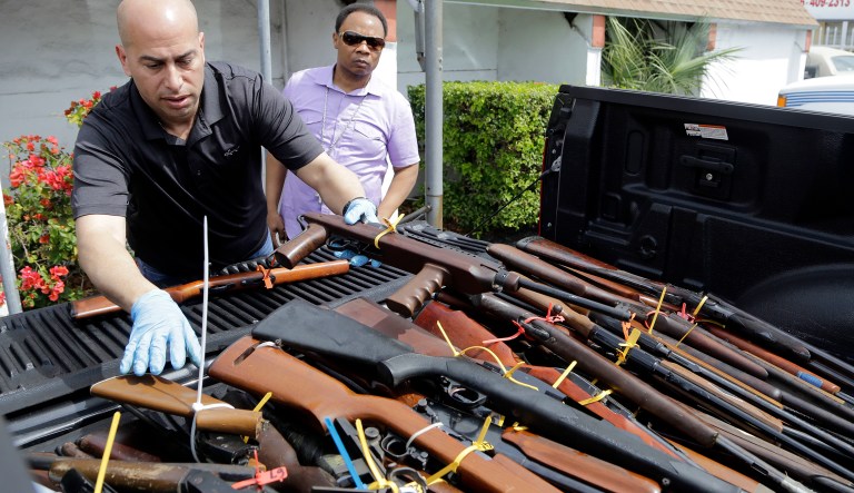 Miami police sergeant Joaquin Freire, left, sorts through rifles that were turned into Miami police during a gun buyback program held at the Jordan Grove Missionary Baptist Church, Saturday, March 12, 2016, in Miami. The event was organized by Rev. Jerome Starling, right, in response to continuing gun violence in the city. Over 100 firearms were collected.