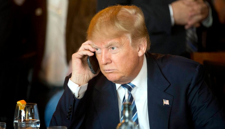 Donald Trump listens to his cellphone at a restaurant.