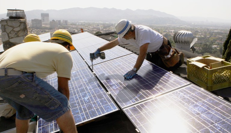 Installers from California Green Design install solar electrical panels on the roof of a home in Glendale, Calif.