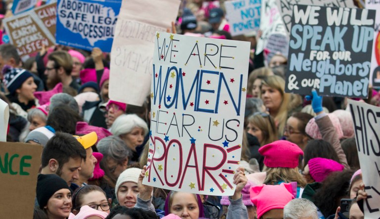 A person holds up a sign saying "We are women, hear us roar" at the Women's March.