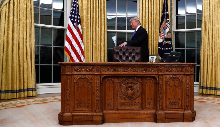 President Trump walks around the Resolute Desk at the White House in Washington.