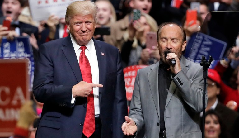 President Donald Trump stands on stage with singer Lee Greenwood as Greenwood sings "God Bless the USA" at a rally Wednesday, March 15, 2017, in Nashville, Tenn.