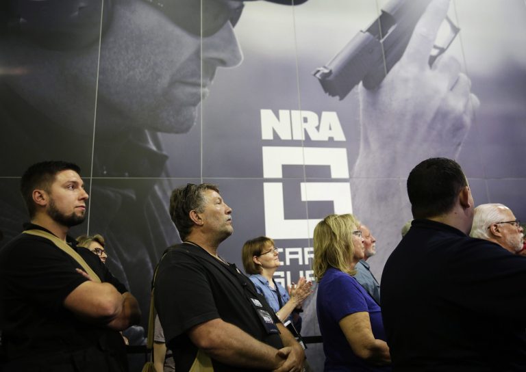 A crowd watches a television from the exhibition hall as President Donald Trump speaks at the National Rifle Association's annual convention in Atlanta, Friday, April 28, 2017.