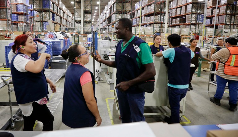 Evens Presendeaux of Haiti (center) speaks with coworkers on the floor of a factory in Tijuana, Mexico. Presendeaux is among about 4,000 Haitians to establish roots in Mexico's northwest corner after the United States abruptly closed its doors late last year. The Mexican government has welcomed them, and they are already having an outsize economic and cultural impact.