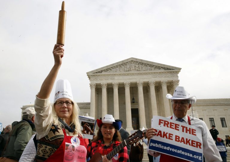 Mary Torres of Falls Church, Va., left, with her daughter Maria Torres, and Eugene Delgaudio, holds up a rolling pin in support of cake artist Jack Phillips, while outside of the Supreme Court, Tuesday, Dec. 5, 2017, during the 'Masterpiece Cakeshop v. Colorado Civil Rights Commission' case in Washington. (AP Photo/Jacquelyn Martin)