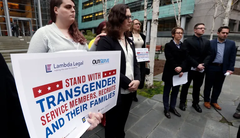 Plaintiffs Cathrine Schmid, second left, and Conner Callahan, second right, listens with supporters during a news conference in front of a federal courthouse following a hearing there in Seattle. U.S. District Judge Marsha Pechman says she won't immediately consider President Trump's new policy banning transgender people from serving in the military. 