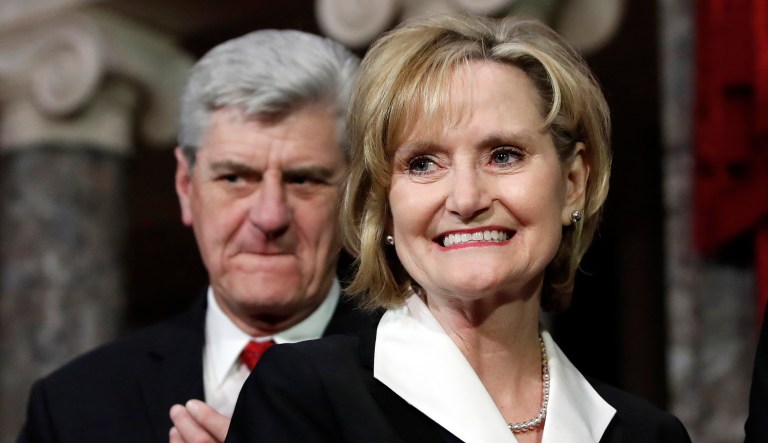 Mississippi Republican Cindy Hyde-Smith, right, smiles next to Mississippi Gov. Phil Bryant, left, at her ceremonial swearing-in at the Old Senate Chamber on Apr. 9, 2018, in the Capitol in Washington. She was appointed by Bryant to succeed Sen. Thad Cochran, R-Miss., who resigned April 1 for health reasons. 
