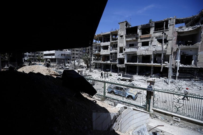 Syrians walk through the destruction in the town of Douma, the site of a suspected chemical weapons attack, near Damascus, Syria, Monday, April 16, 2018. Faisal Mekdad, Syria's deputy foreign minister, said on Monday that his country is "fully ready" to cooperate with the fact-finding mission from the Organization for the Prohibition of Chemical Weapons that's in Syria to investigate the alleged chemical attack that triggered U.S.-led airstrikes. 