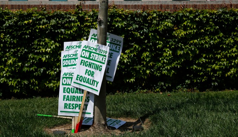 Signs are propped against a tree during a rally outside Ronald Reagan UCLA Medical Center Monday, May 7, 2018, in Los Angeles. Thousands of custodians, security guards, gardeners and other service workers at University of California campuses have started a three-day walkout to address gender pay inequalities and demand higher wages.