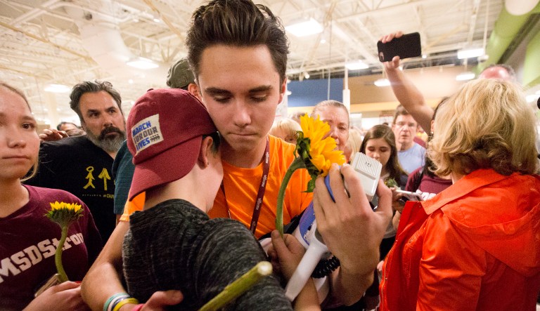 Marjory Stoneman Douglas High School students David Hogg, center rear, and Caspen Becher, hug after a demonstration at a Publix Supermarket in Coral Springs, Fla., Friday, May 25, 2018. Students from the Florida high school where 17 people were shot and killed earlier this year did a "die in" protest at a supermarket chain that backs a gubernatorial candidate allied with the National Rifle Association. Shortly before the the "die-in" Publix announced that is will suspend political donations.