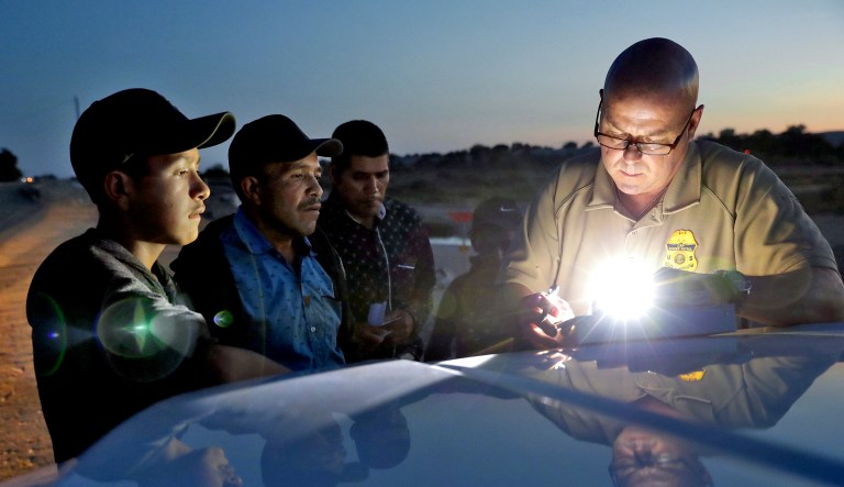 A U.S. Customs and Border Patrol agent gathers information on four Guatemalan nationals, including two men and a pair of 12 and 13-year-old boys, Wednesday, July 18, 2018, in Yuma, Ariz.