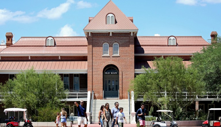 Families and students walk in front of Old Main along the University of Arizona Mall the week before classes start, Friday, in Tucson, Ariz.  