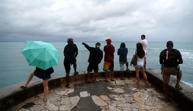People look out over the ocean along Waikiki Beach in a light rain from Tropical Storm Lane, Saturday, in Honolulu.