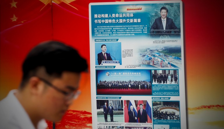 A man walks by a government propaganda billboard promoting Chinese President Xi Jinping's signature "One Belt One Road" outside a subway station in Beijing.