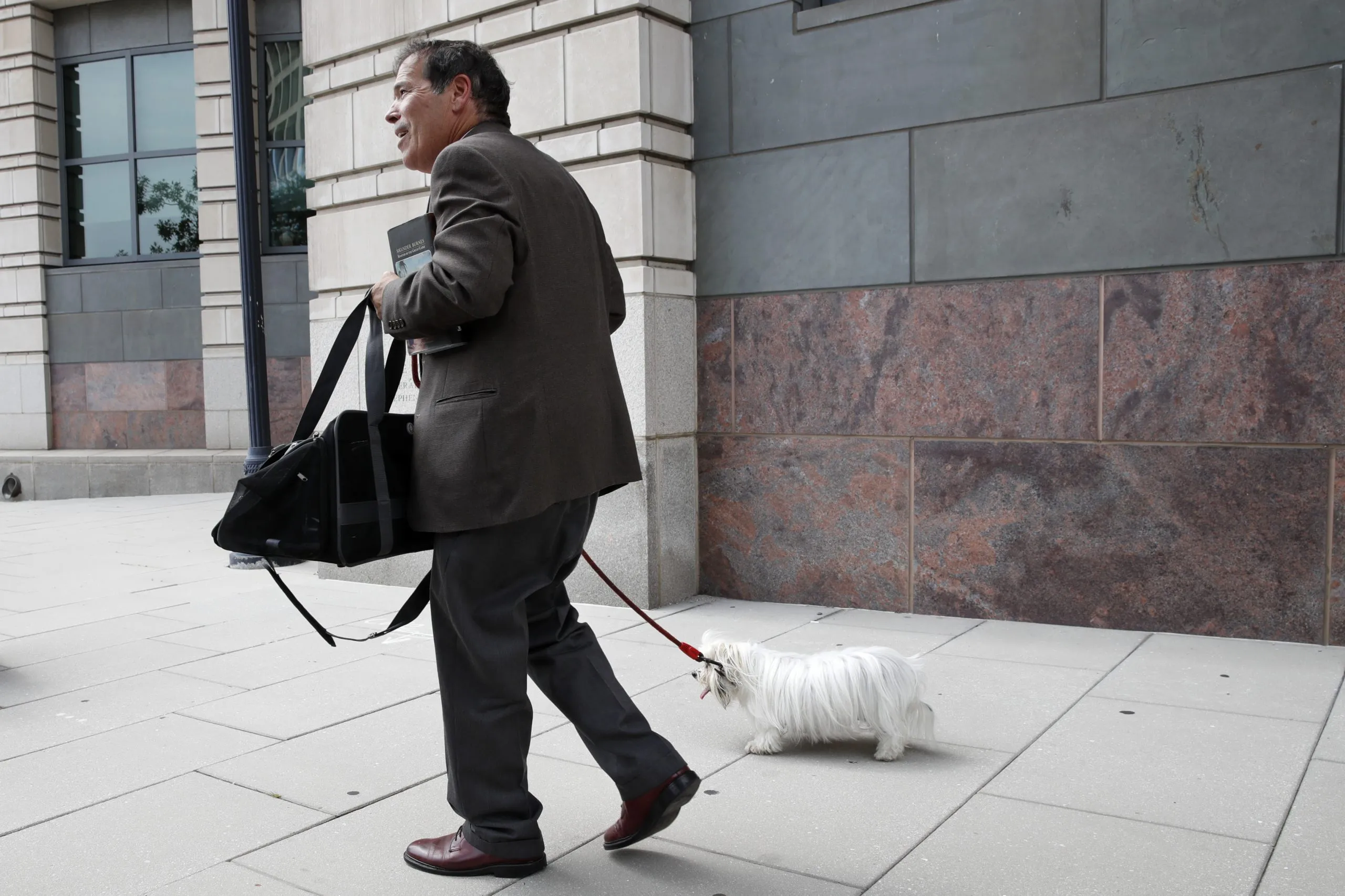 New York radio host Randy Credico, with his dog Bianca, walks away from federal court after after appearing before the grand jury hearing evidence in special counsel Robert Mueller's investigation of Russian interference in the 2016 presidential election Friday in Washington. 