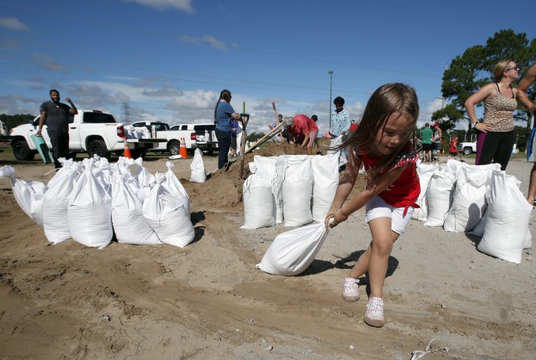 Chloe Heeden, 4, from Virginia Beach, Va., drags a sandbag to her father's car, Wednesday, Sept. 12, 2018, in Virginia Beach, Va., as Hurricane Florence moves towards the eastern shore. With the story staying south, the all clear has been signaled on Friday.