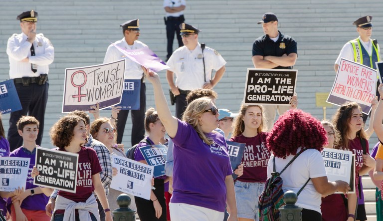In this Monday, June 25, 2018 file photo, pro-choice and anti-abortion advocates hold signs as they demonstrate in front of the Supreme Court in Washington. Among those riveted by the drama of Brett Kavanaugh's Supreme Court nomination are the rival sides in America's abortion debate, each convinced that the nationwide right to abortion is at stake.