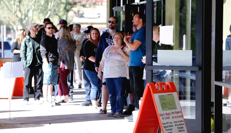 Voters wait in line to cast their ballots at a relocated polling station in Chandler, Ariz.