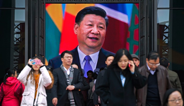 Visitors walk past the main entrance door as an electronic display panel showing video footage of Chinese President Xi Jinping at an exhibition marking the 40th anniversary of China's reform and opening up at the National Museum of China in Beijing, Thursday, Nov. 15, 2018. Chinese President Xi Jinping has promised to open China's growing consumer market wider at the recent import fair meant to help defuse complaints Beijing abuses the global trading system, but he offered no response to U.S. and European complaints about technology policy and investment curbs. 