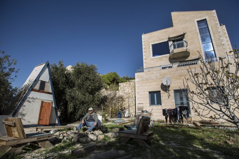 FILE - In this Jan. 17, 2016 file photo, Moshe Gordon sits outside his guest house advertised on the Airbnb international home-sharing site, in the Nofei Prat settlement in the West Bank. On Tuesday, Nov. 20, 2018, Israel's Tourism Minister Yariv Levin threatened the vacation rental company Airbnb with higher taxes, restrictions and legal repercussions over its decision to remove listings from Israeli settlements in the West Bank.