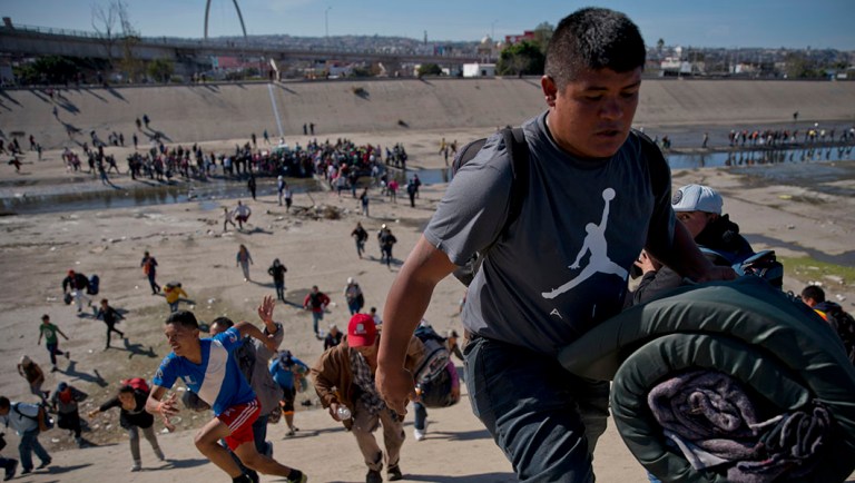 Migrants move up a riverbank at the Mexico-U.S. border after getting past a line of Mexican police at the Chaparral border crossing in Tijuana, Mexico.