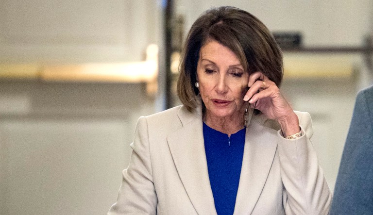 House Speaker Nancy Pelosi of Calif. stands in a hallway and speaks on the phone as she arrives back at the Capitol building after meeting with President Trump about border security in the Situation Room of the White House in D.C.