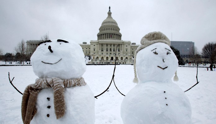 The U.S. Capitol is seen behind some snowmen during a snowstorm.