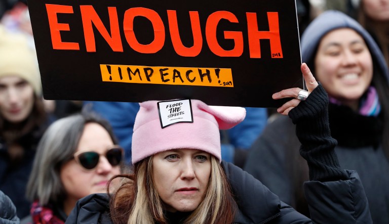 A woman holds a sign expressing her opinion about impeaching President Donald Trump at a rally organized by Women's March NYC at Foley Square in Lower Manhattan, Saturday, Jan. 19, 2019, in New York. 