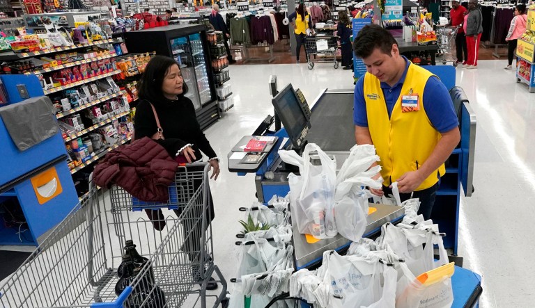 Walmart associate Luis Gutierrez, center, checks out a customer's items at a Walmart Supercenter in Houston.