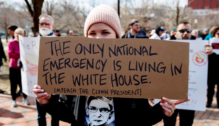 Cat McKay of Alexandria, Va., holds an impeachment sign during a protest.