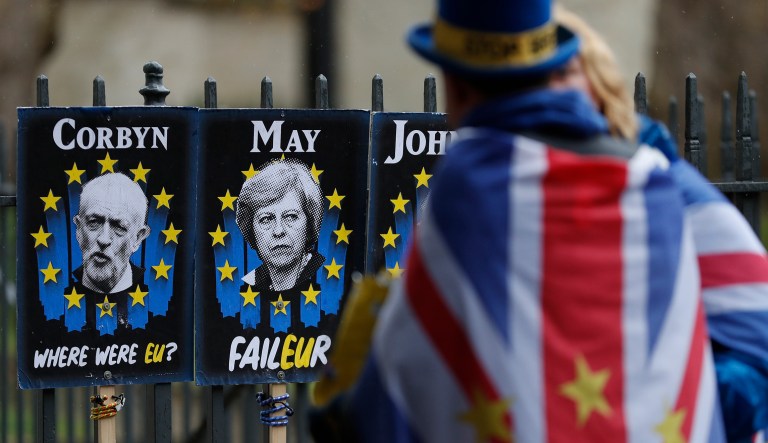 Anti-Brexit protester looks at placards showing pictures of British politicians as she demonstrates outside the Houses of Parliament in London, Tuesday, April 2, 2019.