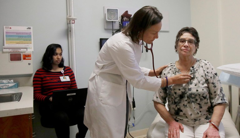 Dr. Megan Mahoney, center, examines patient Consuelo Castaneda, right, as medical scribe Anu Tirapasur documents the visit at the Stanford Family Medicine office in Stanford, Calif.