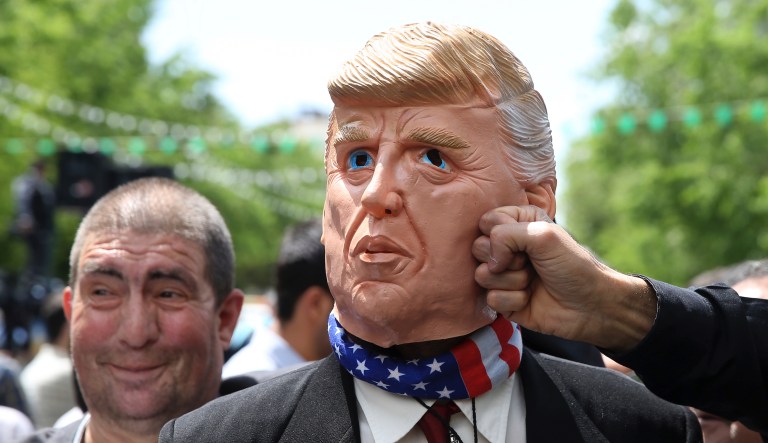 An Iranian protester pretends to punch a mask mocking President Donald Trump during a rally after Friday prayer in Tehran, Iran, Friday, May 10, 2019. 