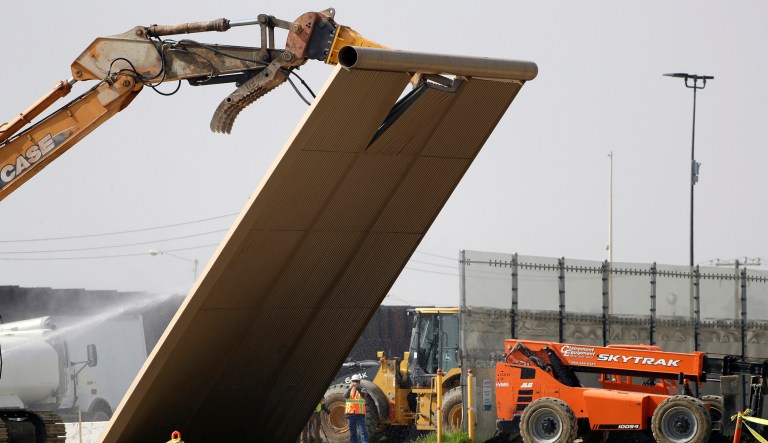 A border wall prototype falls during demolition at the border between Tijuana, Mexico, and San Diego.