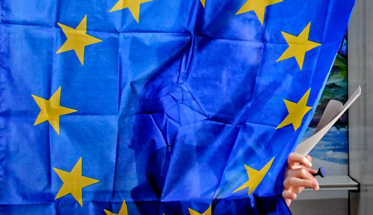 A woman exits a voting cabin with curtains depicting the European Union in Baleni, Romania.
