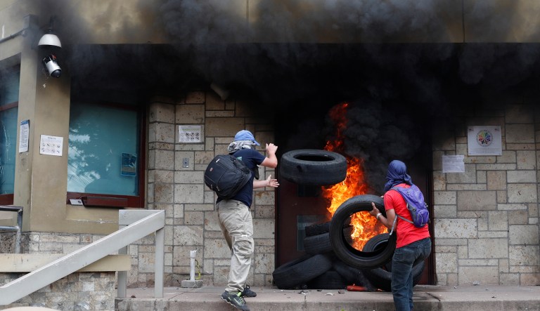 Protesters add tires to a fire outside the main entrance into the U.S. Embassy during a protest against the government of President Juan Orlando Hernandez, in Tegucigalpa, Honduras, Friday, May 31, 2019. Protesters are demanding the government revoke decrees that they say would lead to massive, uncompensated layoffs of public employees and the privatization of state hospitals.