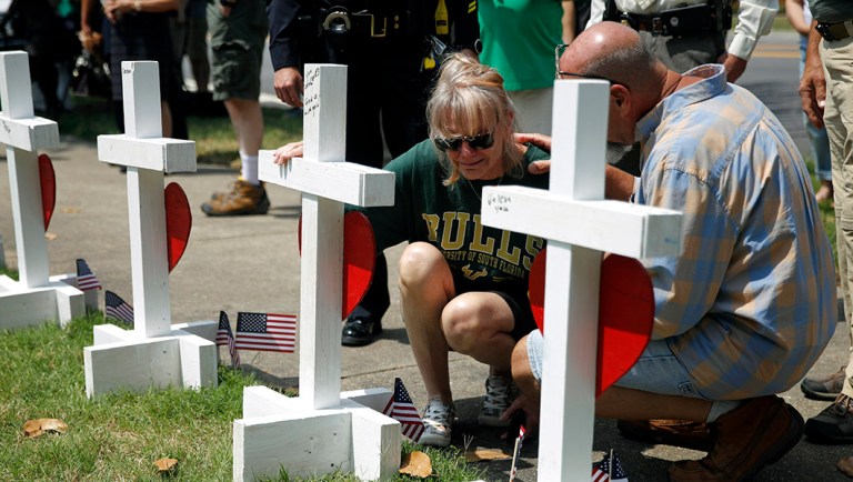 A woman who did not wish to be identified kneels beside a cross.