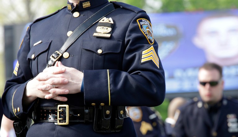 A member of the police honor guard has his badge covered in mourning as he arrives for the funeral mass for New York City police officer  Brian Moore, Friday, May 8, 2015, at the St. James Roman Catholic church in Seaford, N.Y.  As many as 30,000 police officers from across the United States are expected to pay their respects at the Long Island funeral for the young  police officer slain on patrol.
