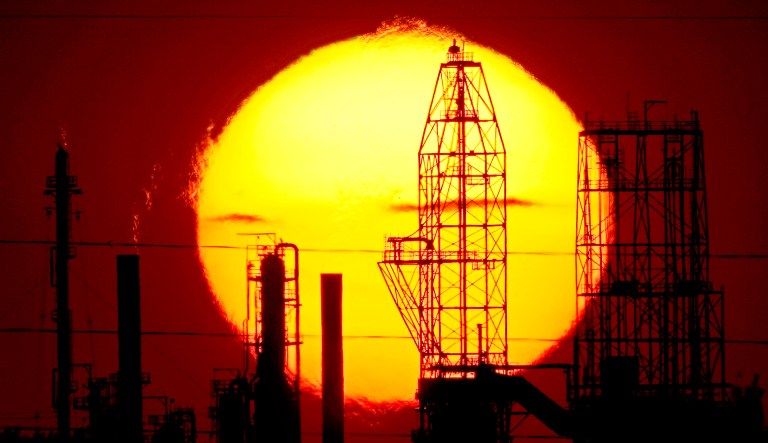 The National Cooperative Refinery Association oil refinery is silhouetted against the setting sun in McPherson, Kan.