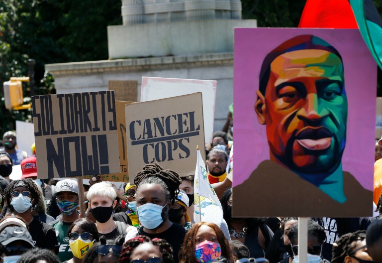 People hold signs during a Caribbean-led Black Lives Matter rally at Brooklyn's Grand Army Plaza, June 14, 2020, in New York.