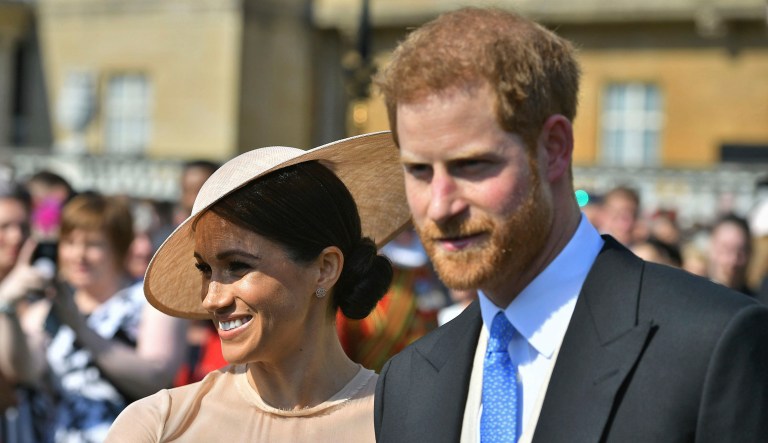 Meghan, the Duchess of Sussex, walks with her husband, Prince Harry, as they attend a garden party at Buckingham Palace in London. 
