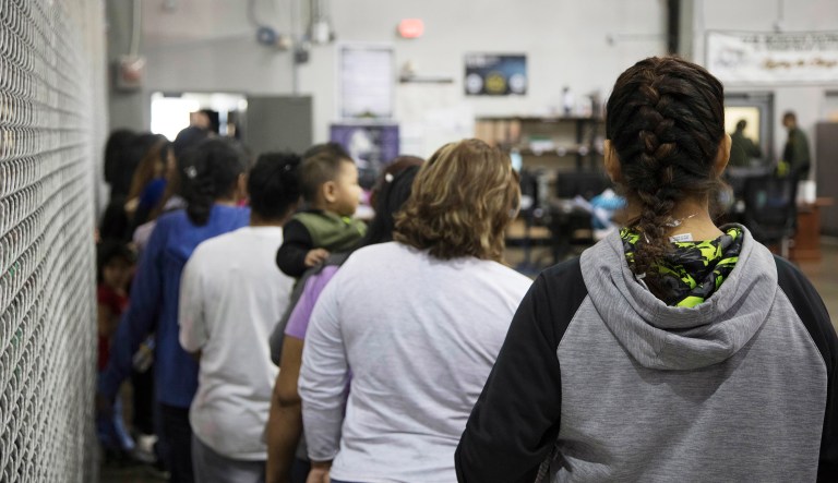 People who've been taken into custody related to cases of illegal entry into the United States, stand in line at a facility in McAllen, Texas.