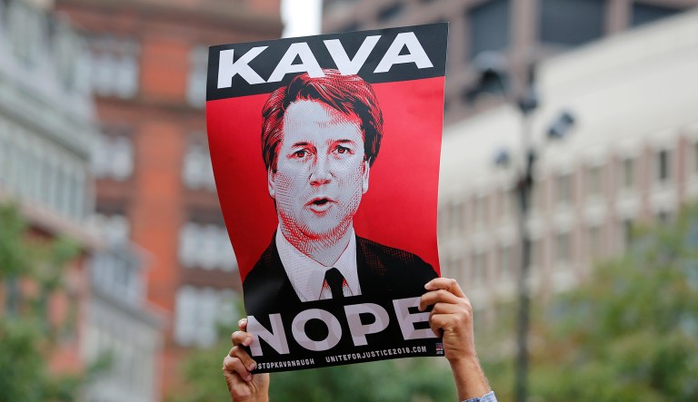 A protester holds a sign in opposition to Judge Brett Kavanaugh at a rally at City Hall ahead of an appearance by Sen. Jeff Flake, R- Ariz., at the Forbes 30 Under 30 Summit, Monday, Oct. 1, 2018, in Boston.